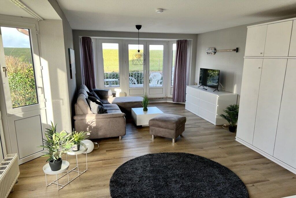 Una sala de estar moderna con sofá, reposapiés, mesa de centro y televisor.