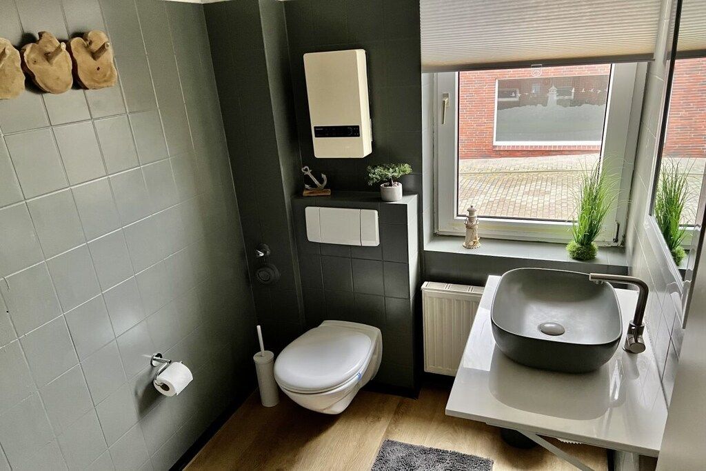 A compact bathroom with a toilet, sink, and a small window.