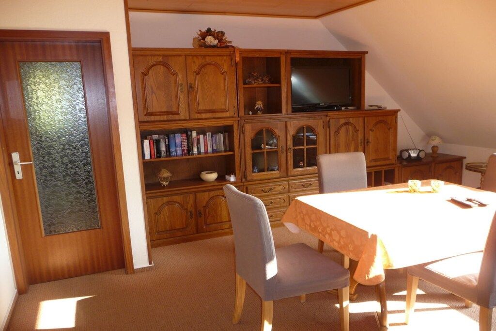 A dining area with a table, chairs, and a television set.