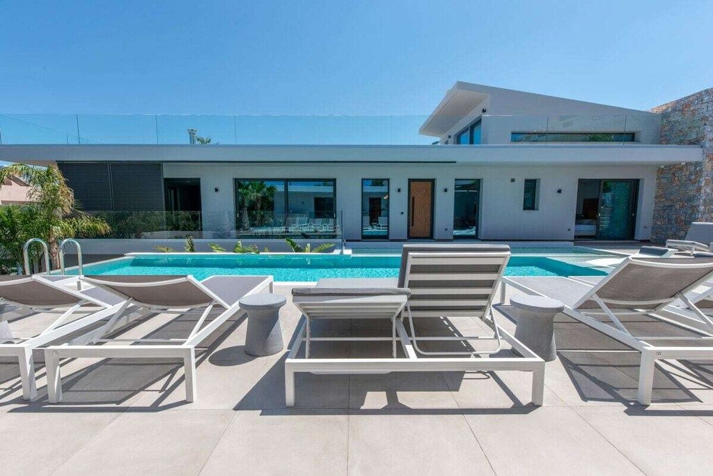 A modern house with a swimming pool and lounge chairs.