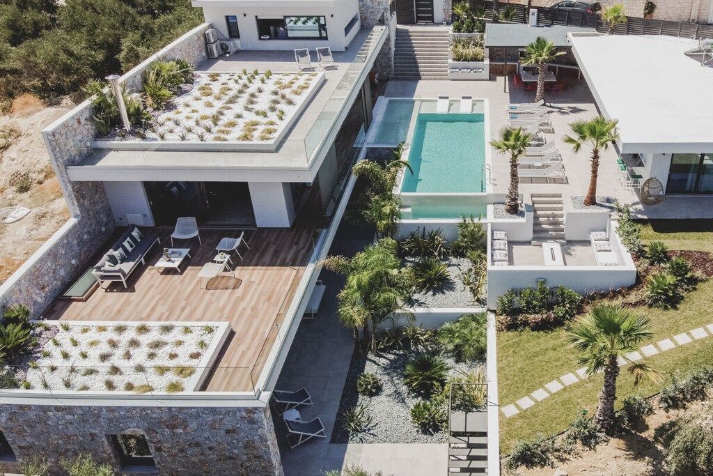 Un resort moderno con piscina en la azotea, mobiliario exterior y un jardín ajardinado.