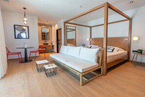 Ein modernes Schlafzimmer mit einem Himmelbett, einer Couch, einem kleinen Tisch und einem roten Sessel.