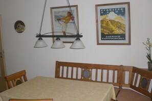 Ein Essbereich mit Tisch und Stühlen, einem Poster an der Wand und einer Hängelampe.