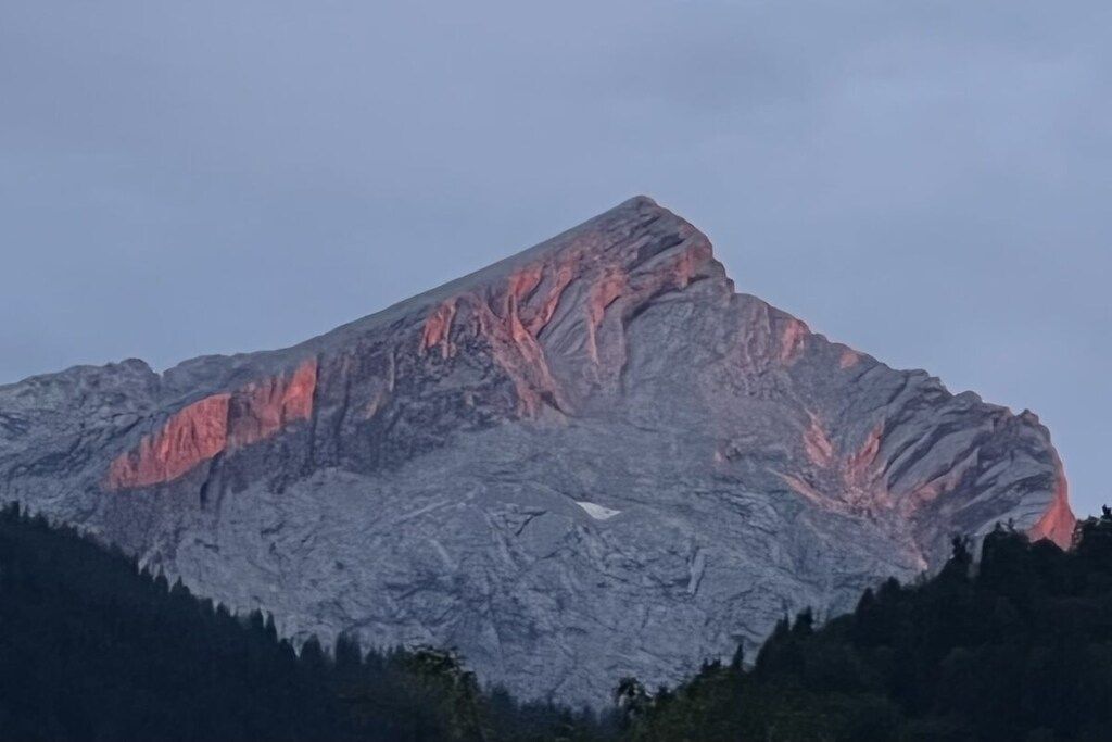 A mountain with a prominent peak and a forested base.