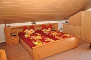 Ein Schlafzimmer mit einem hölzernen Bett, einem Nachttisch, einer Kommode und einem Fenster mit Jalousien.