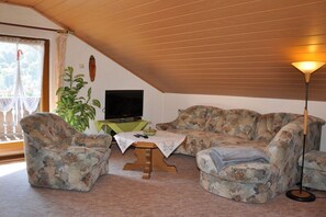 Ein Wohnzimmer mit Holzboden, einem Fernseher, einem Sofa, einem Couchtisch und einer Stehlampe.