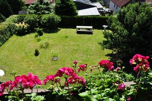 Ein gepflegter Garten mit einer Bank, umgeben von üppigem Grün und blühenden Pflanzen.
