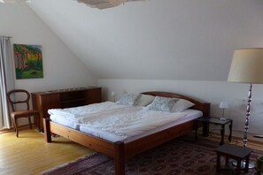 Ein Schlafzimmer mit einem hölzernen Bett, einem Schreibtisch, einem Stuhl, einer Lampe und einem Bild an der Wand.