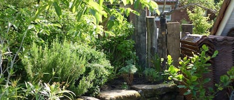 Un jardín con muro de piedra, plantas diversas y cerca de madera.