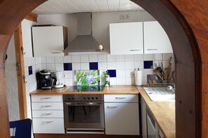 Une cuisine de taille réduite avec des meubles blancs, un four en acier inoxydable et une machine à café.