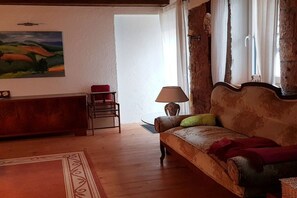 Ett vardagsrum med en soffa, en lampa, en fåtölj och en tavla på väggen.