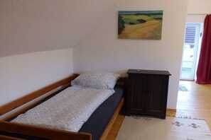 Une petite pièce avec un lit simple, une armoire en bois sombre et un tableau accroché au mur.