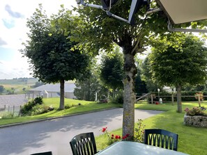 An outdoor seating area with a table and chairs, surrounded by greenery and a view of the countryside. - Holiday Home “Gîte La Gazeille” with Mountain View and Wi-Fi (Les Estables)