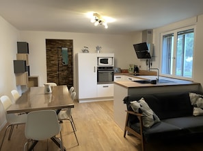 A modern kitchen with a dining area, a sofa, and a TV. - Holiday Home “Gîte La Gazeille” with Mountain View and Wi-Fi (Les Estables)