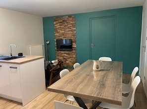 A modern kitchen with a wooden countertop, a built-in TV, and a teal accent wall. - Holiday Home “Gîte La Gazeille” with Mountain View and Wi-Fi (Les Estables)