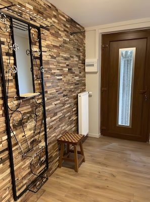 A room with a wooden wall, a radiator, a door with a window, and a small stool. - Holiday Home “Gîte La Gazeille” with Mountain View and Wi-Fi (Les Estables)
