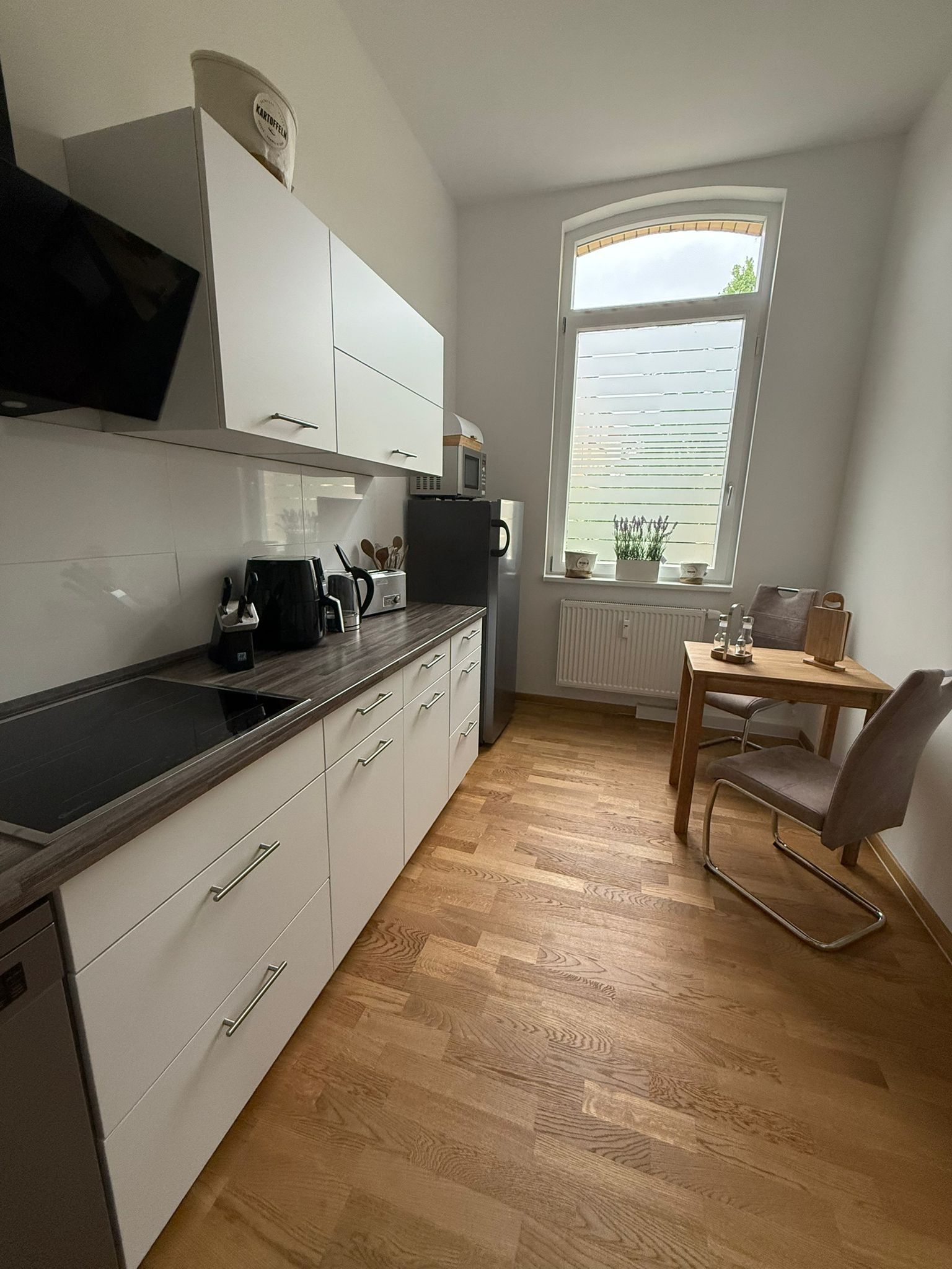 A compact kitchen with white cabinets, a microwave, and a window with blinds.
