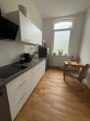 A compact kitchen with white cabinets, a microwave, and a window with blinds. - Apartment '5' with Wi-Fi (Erfurt)