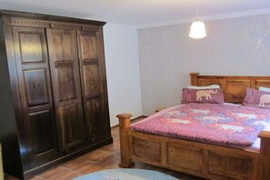 A bedroom with a wooden bed, a large wardrobe, and a hanging light fixture. - Heideblockhaus Harmonie (Neuenkirchen)