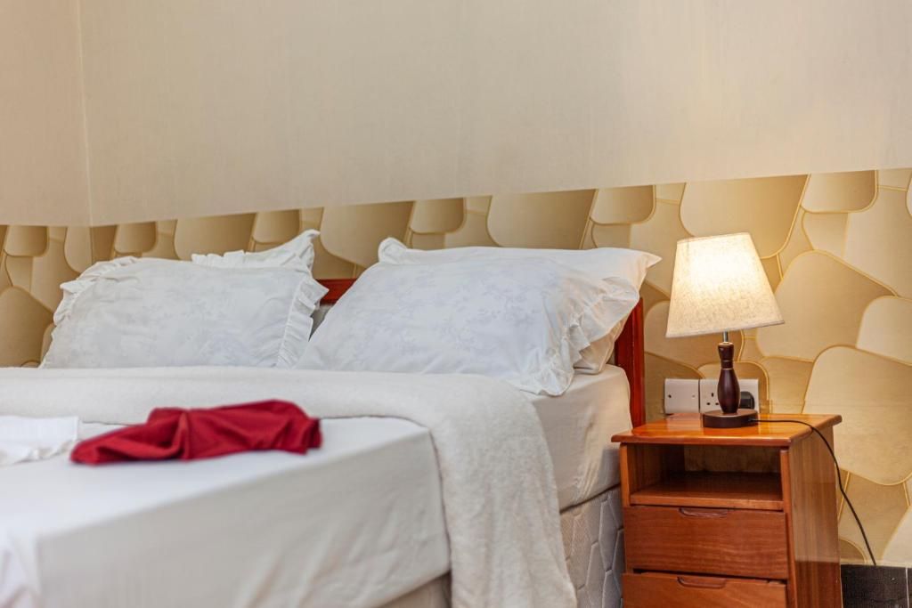 A hotel room with a bed, a nightstand with a lamp, and a wall with a textured pattern.