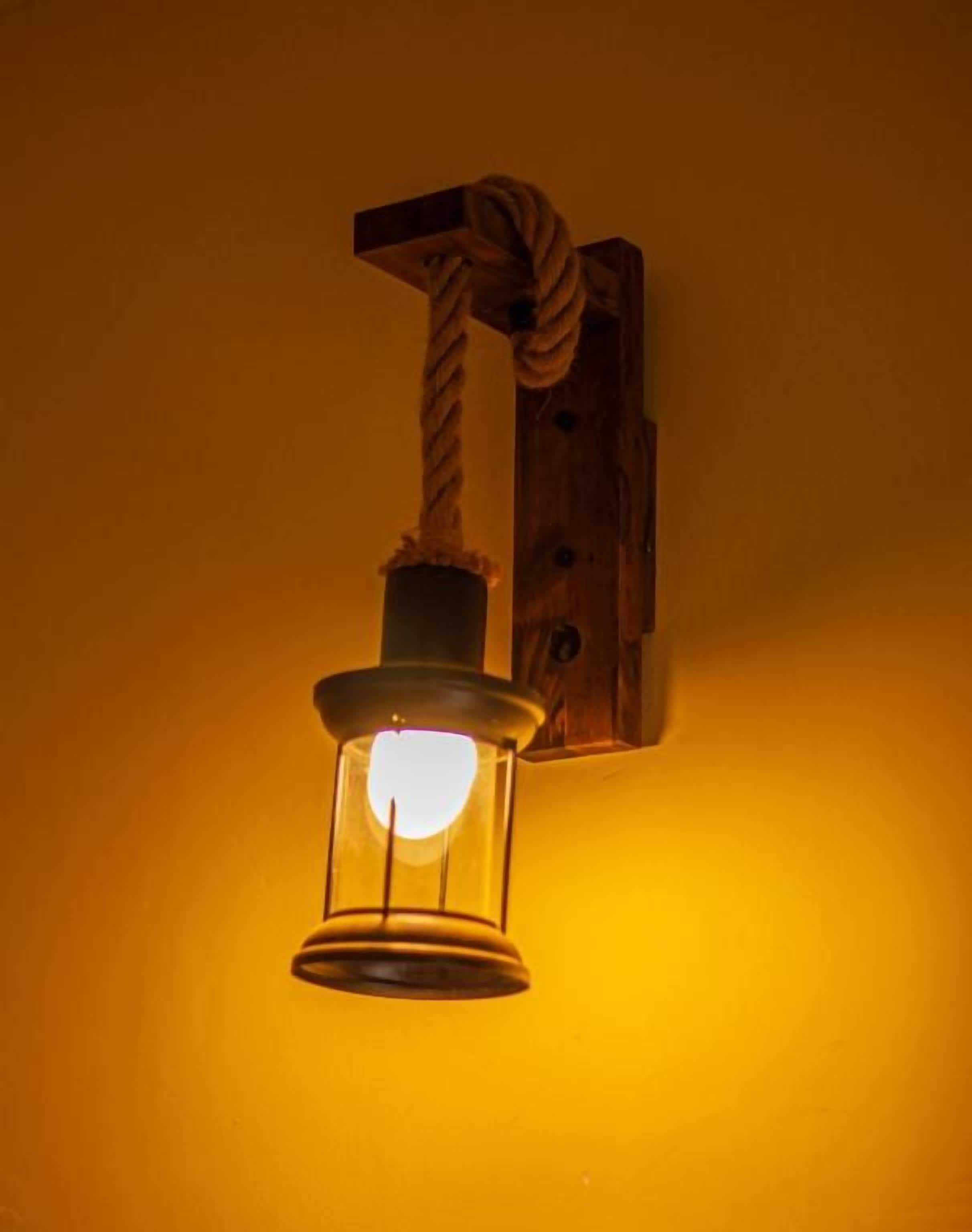 A wall-mounted light fixture with a rope and a cylindrical object.