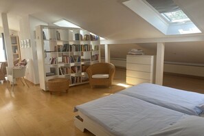 A spacious room with a large bookshelf, a bed, a chair, and a desk. - Studio apartment Diessen (Diessen)