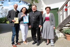 Vier Personen stehen vor einem Gebäude mit einer Treppe und einer grünen Tür.