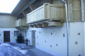Un bâtiment dont le sol est recouvert de neige, doté de balcons en bois et orné d’un petit sapin de Noël.
