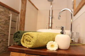 A bathroom with a wooden vanity, a towel, a flower, and a shower. - Holiday apartment with 1 bedroom (Freyung)