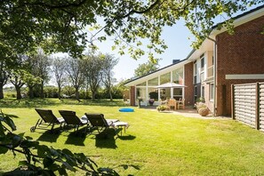 Un jardin avec une piscine, des chaises longues et un patio couvert.
