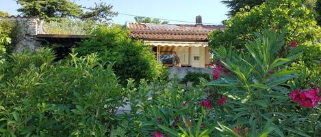 A house with a tiled roof, surrounded by lush greenery and flowering plants.