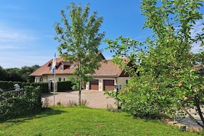 A two-story house with a red-tiled roof, a driveway, and a well-maintained lawn. - Holiday apartment with 1 bedroom (Kirchenpingarten)