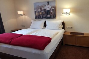 A hotel room with a bed, two bedside tables, a red blanket, a painting on the wall, and two wall-mounted lamps. - Eldorado Holiday Apartment Southwind (Bolsterlang)