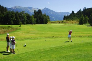 A golf course with a mountainous backdrop, a putting green, and players in action. - Eldorado Holiday Apartment Southwind (Bolsterlang)