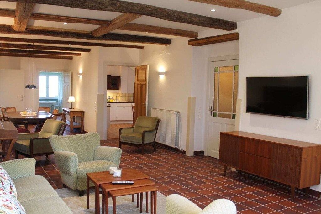 Una sala de estar con televisor, muebles de madera y piso de baldosas.