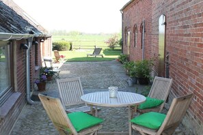 Ein Innenhof mit einem Backsteingebäude, einem runden Tisch mit Stühlen und einer Rasenfläche.