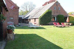 A brick building with a sloped roof, a grassy yard, and outdoor seating. - Holiday home with 5 bedrooms (Osterholz-Scharmbeck)
