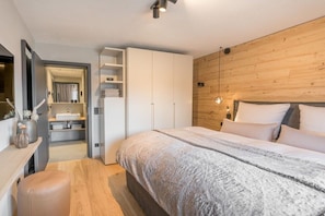 Ein Schlafzimmer mit einem Bett, Holzvertäfelung, einem Kleiderschrank und einem Nachttisch.