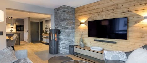 A modern living room with a stone accent wall, a flat-screen TV, and a fireplace.