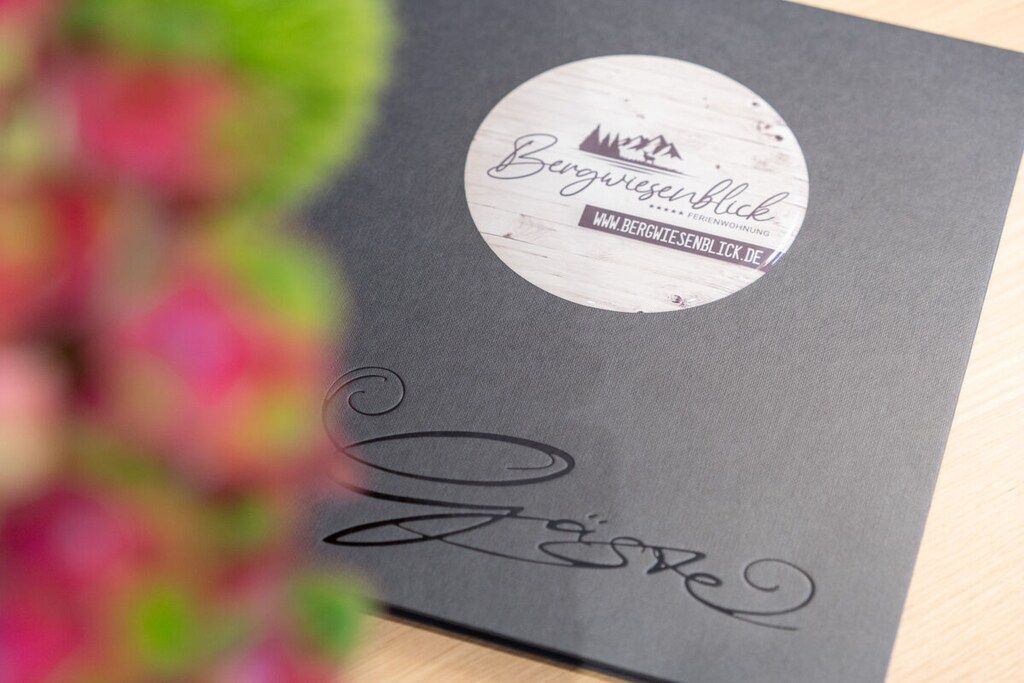 A black folder with a circular label that reads 'Bergwieserblick' and a website address.