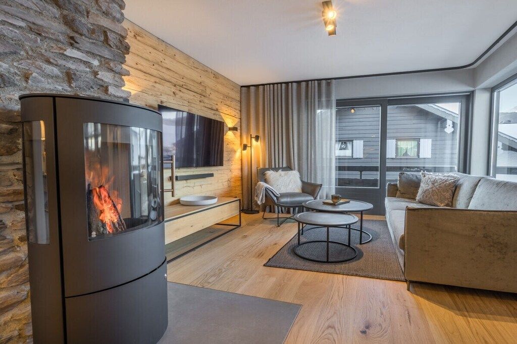 A modern living room with a stone wall, a fireplace, a sofa, and a television.