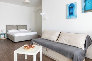 A modern bedroom with a bed, a sofa, a small table with a bowl of fruit, and a floor lamp. - Largo Molina Studio II by Wonderful Italy (Bologna)