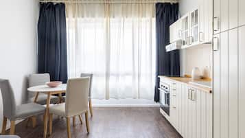 A compact kitchen with a dining area, featuring a table with chairs, a stove, and cabinets.