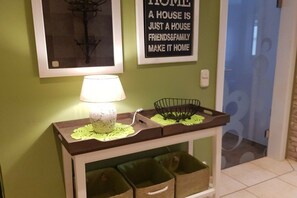 Un couloir avec une lampe de table, une citation encadrée accrochée au mur et des paniers de rangement placés sous une console.