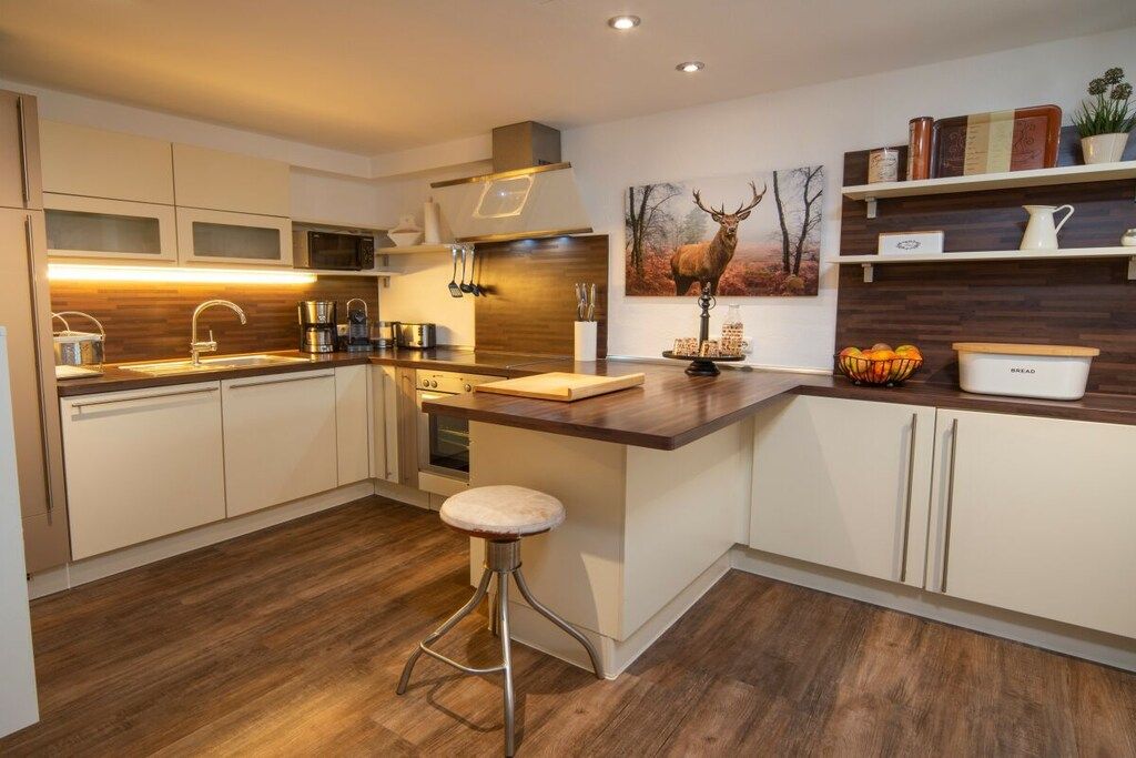 Una cocina moderna con una isla central, electrodomésticos de acero inoxidable y suelo de madera.