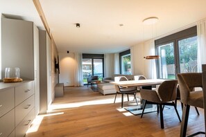 Eine moderne Küche mit Essbereich, Holzboden und großen Fenstern.