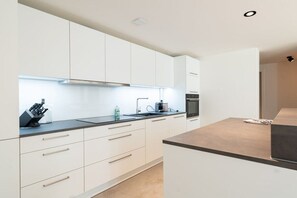 Eine moderne Küche mit weißen Schränken, einer schwarzen Arbeitsplatte und einem eingebauten Backofen.