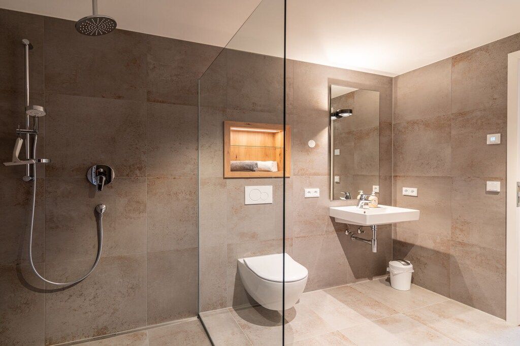 Une salle de bain moderne avec une douche à parois de verre, des toilettes et un lavabo avec un miroir au-dessus.