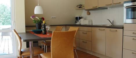 Una cocina moderna con comedor, que incluye una mesa con sillas, una lámpara colgante y un ventanal que proporciona luz natural.