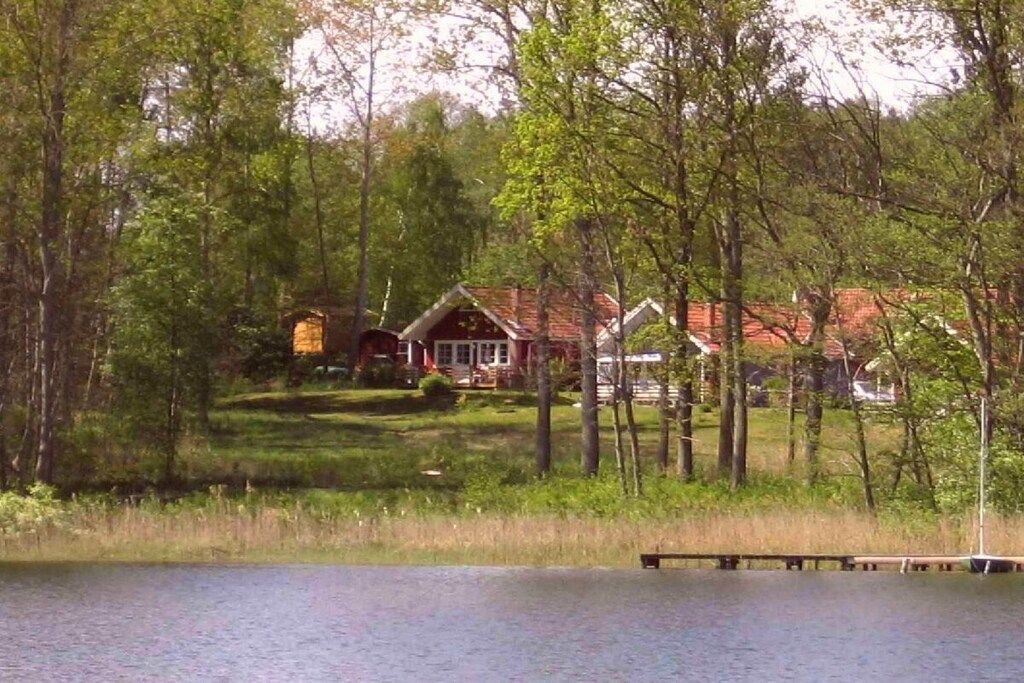 Un chalet au bord du lac, doté d’un quai, entouré d’arbres et d’une zone herbeuse.